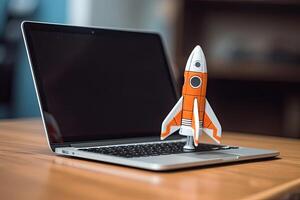 Rocket taking off from laptop screen on top of office desk, successful startup concept, photo