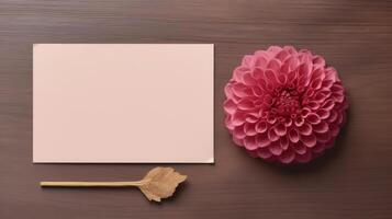 Top View of Blank Pink Paper Card Mockup with Beautiful Dahlia Flower on Wooden Table, . photo