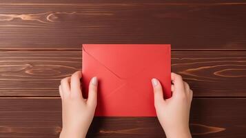 Top VIew Photo of Female Holding a Red Envelope Mockup on Wooden Table. .