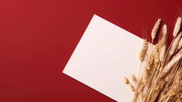 Top View of Blank White Paper with Dried Wheat on Red Background and Placement. Vintage Delicate Business or Wedding Card Design. . photo