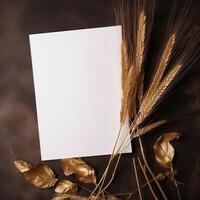 Top View of Blank White Paper with Golden Wheat, Leaves on Brown Texture Background and Placement. Vintage Delicate Business or Wedding Card Design. . photo