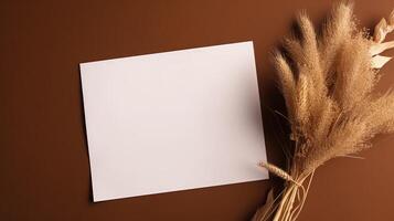 Top View of Blank White Paper with Dry Pampas Grass on Shiny Brown Background for Vintage Delicate Business or Wedding Card Design. . photo