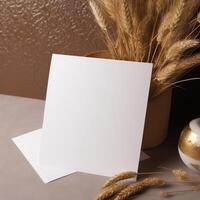 Blank White Invitation Card with Golden Floral Embossing Mockup, Dried Wheat Grass Vase. . photo
