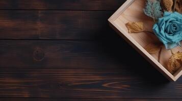 Closeup Vintage Wooden Box Full of Blue Rose and Dried Leaves on Plank Texture Table Top. . photo