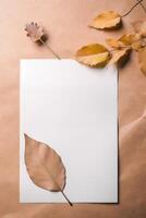 Top View of Blank White Paper Mockup with Dried Leaves on Brown and Peach Background. . photo