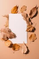 Blank White Paper and Autumn Leaves on Peach Background. . photo