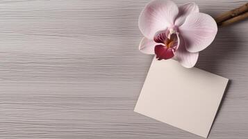 Top View of Blank Paper Card Mockup and Orchid Flower on Gray Wooden Texture Table, . photo