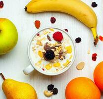 desayuno con cuenco de leche, cereales y rojo frutas en blanco mesa y Fresco fruta. foto