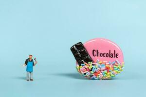 Miniature people, Chef with chocolate cookie on a blue  background. World Chocolate Day Concept photo