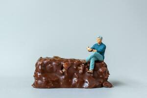 Business man sitting on chocolate bars with gray background. World Chocolate Day Concept photo