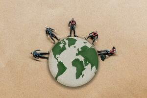 Miniature people standing on the globe with paper background photo