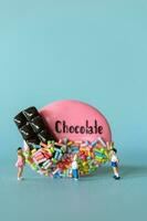 Miniature Kids with chocolate cookie standing against a blue background. World Chocolate Day Concept photo