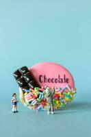 Miniature Kids with chocolate cookie standing against a blue background. World Chocolate Day Concept photo