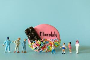 Miniature Kids with chocolate cookie standing against a blue background. World Chocolate Day Concept photo