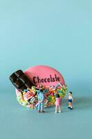 miniatura niños con chocolate Galleta en pie en contra un azul antecedentes. mundo chocolate día concepto foto