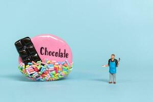 Miniature people, Chef with chocolate cookie on a blue  background. World Chocolate Day Concept photo