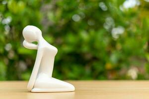 Ceramic Yoga Figurine of Woman doing yoga pose on wooden floor and green leaf  background photo