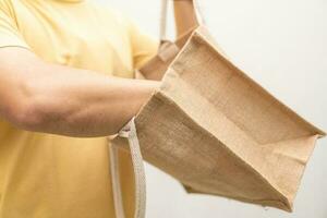 Man holding jute bag or sack bag on white background. Reusable shopping bag. Plastic free. Eco friendly concept. Sack bag for reusable shopping lifestyles, ecology business concept. photo