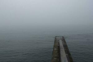 Fog over the morning summer sea. The breakwater in the fog. photo