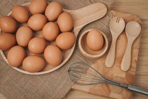 parte superior ver de huevos en de madera plato con de madera cuchara y tenedor en madera mesa. foto