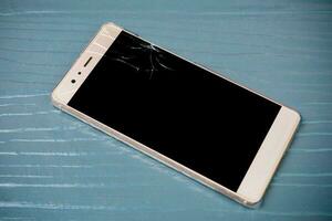 Smartphone with broken screen on wooden photo