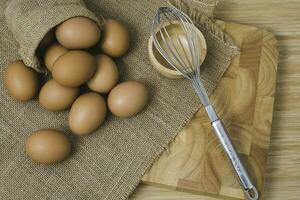 Kitchen metal wire and raw eggs on the wooden board photo