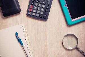 Notebook, pen, Magnifier, calculator and tablet pc, on wood table background. Business concept.. photo