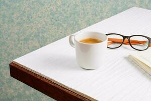 Cup of coffee and stationary on wooden table photo