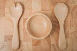 conjunto de tenedor, cuchara y plato madera en de madera mesa foto