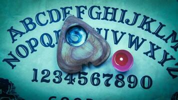 Halloween game with Ouija board. Pointer with magnifying glass and tea red candle on planchette. photo