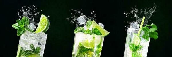 Glasses of Mojito with splashes and flying ice cubes on black and green background in bar photo