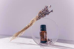 A bottle with lavender essential oil on a lilac background. The concept of aromatherapy and relaxation photo