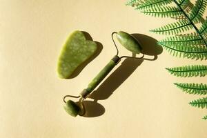 Jade Gua sha scraper and facial massager on beige background. photo