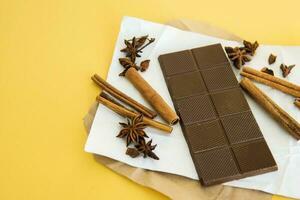 Milk chocolate and cinnamon sticks close-up. Photos in warm colors. Sweetness. World chocolate day. Macro.