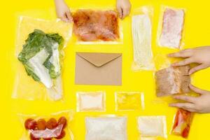 Hands holding bags of food. A set for delivering food for dinner on a yellow background. photo