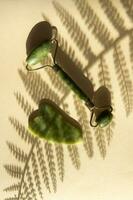 Jade Gua sha scraper and facial massager on beige background. photo