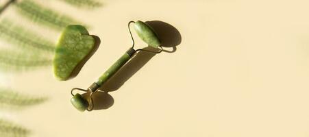 Jade Gua sha scraper and facial massager on beige background. Banner. photo