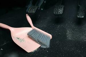 use broom and trash shovel to clean in the carpet area under the accelerator pedal and car coupling photo