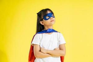 retrato de pequeño niña vestido arriba como un héroe, aislado en amarillo antecedentes foto