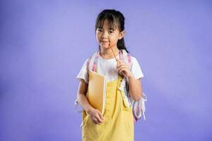 cute asian schoolgirl posing on purple background photo