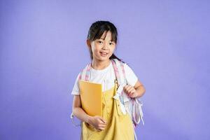 cute asian schoolgirl posing on purple background photo