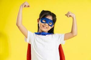 Portrait of little girl dressed up as a hero, isolated on yellow background photo