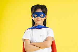 retrato de pequeño niña vestido arriba como un héroe, aislado en amarillo antecedentes foto