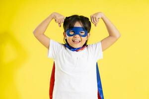 Portrait of little girl dressed up as a hero, isolated on yellow background photo