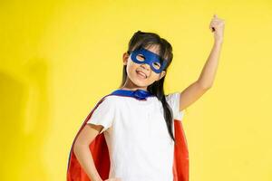 Portrait of little girl dressed up as a hero, isolated on yellow background photo