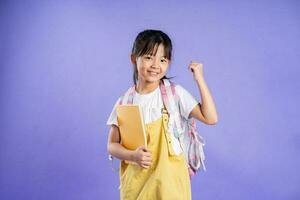 cute asian schoolgirl posing on purple background photo