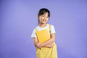 linda asiático Chica de escuela posando en púrpura antecedentes foto