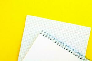 blanco bloc y cuaderno en un jaula en un amarillo antecedentes. foto
