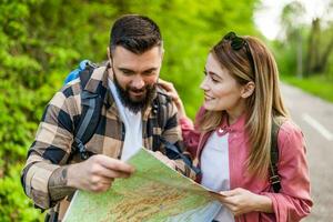 Happy couple hiking in nature and looking at map. Couple enjoying their vacation. photo