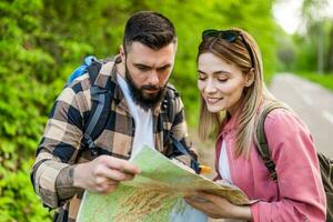 Happy couple hiking in nature and looking at map. Couple enjoying their vacation. photo